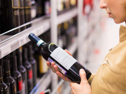 Woman reading the back label of a wine bottle