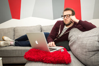 man relaxing on a couch with laptop
