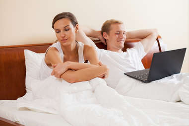 distracted man and annoyed woman in bed