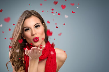 Woman blowing rose petals towards camera