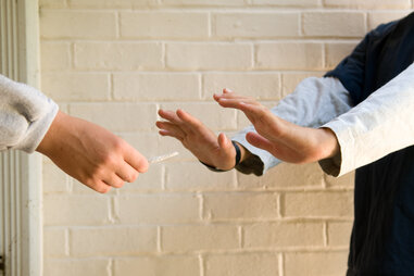 teen boy refusing marijuana cigarette from another boy