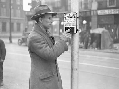 man pressing crosswalk button