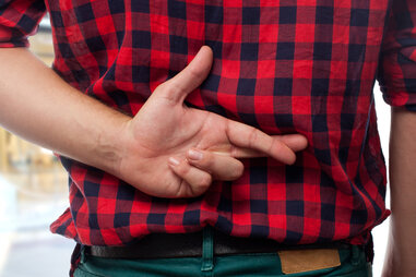 man with red shirt fingers crossed