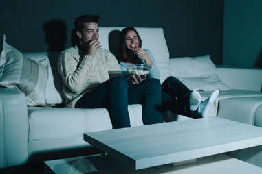 couple watching a movie on the couch with popcorn