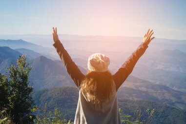 young standing before a forest mountain happy