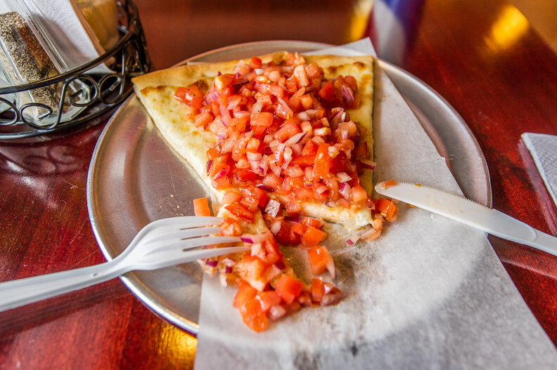 a cut piece of pizza with too many toppings, and a knife and fork