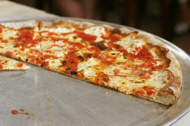 half a plain cheese pizza pie on a metal tray