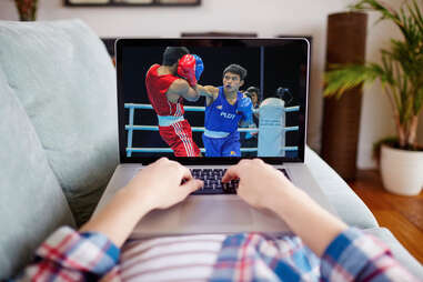 Man streaming boxing match on his Macbook laptop