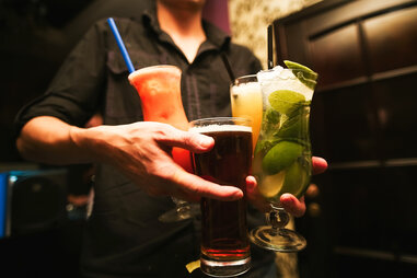 man carrying lots of drinks cocktails