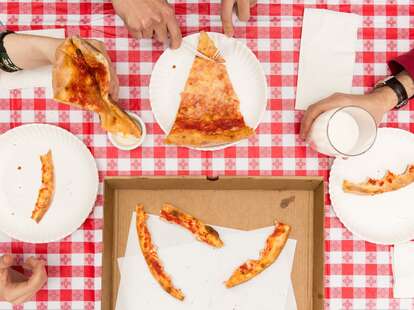 group eating cheese pizza on checkered tablecloth