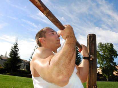 man doing pullup in sunny park