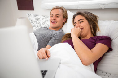 couple in bed on laptop watching movie