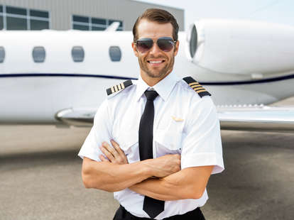 Handsome pilot standing in front of plane