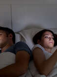 man and woman in bed on smartphones