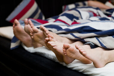 Two pairs of feet in bed