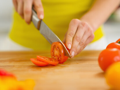 woman cutting tomatoes with a chef’s knife