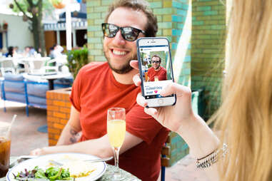 Guy having his picture taken at brunch by girlfriend