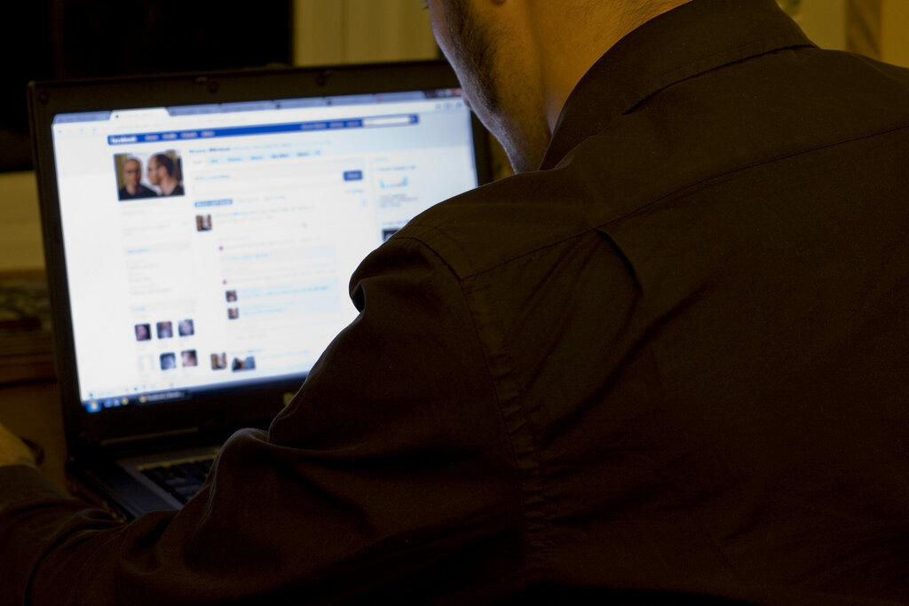 man using Facebook on a laptop