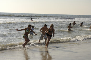 Kids joyfully running away from wave