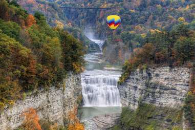 a hot air balloon over a large forest waterfall