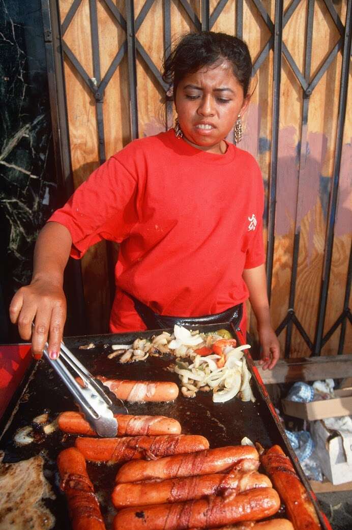 Woman grilling bacon-wrapped hot dogs