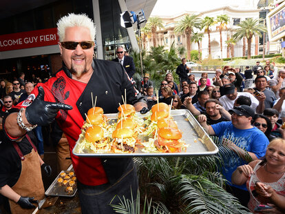 Guy Fieri Holding Plate of Burgers