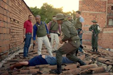 U.S. Drug Enforcement Agency (DEA) Officers stand over Pablo Escobar's dead body after years of chasing the elusive drug trafficker.