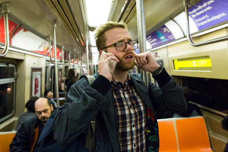 man talking on phone on subway car