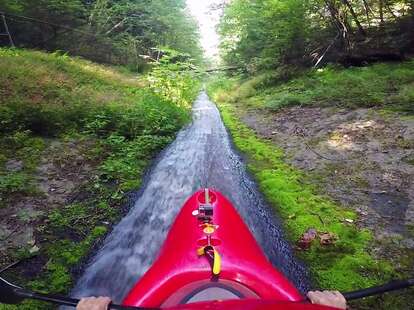 kayak riding down drainage ditch