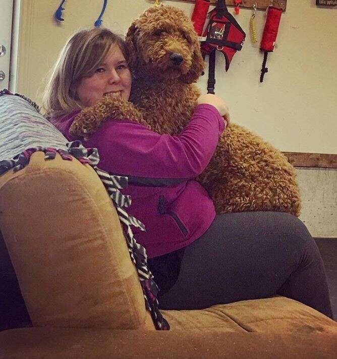 woman hugging dog on couch