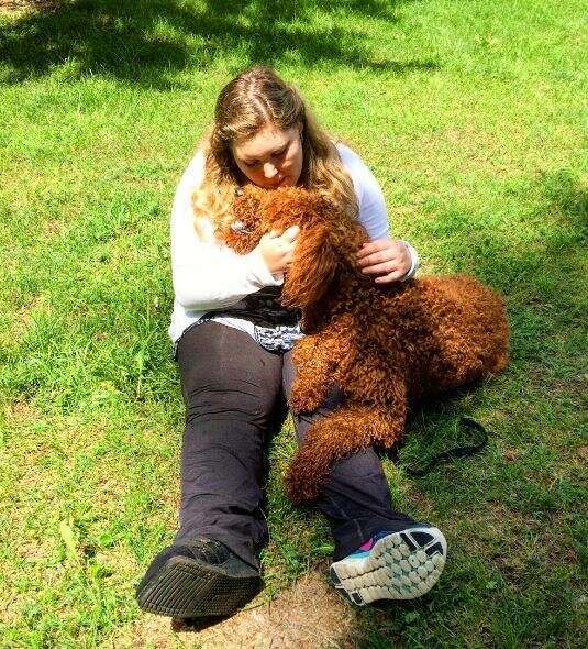 woman hugging service dog on grass