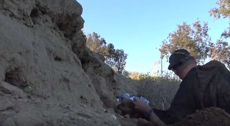 man crawls into tiny cave to save abandoned puppies