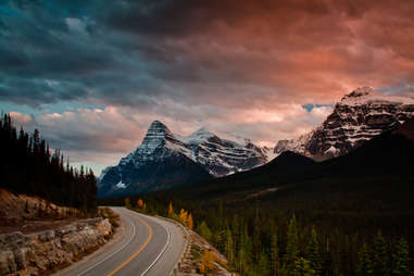 columbia icefields parkway leading toward mountains at sunset