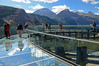 people walking along a glass bridge near mountains