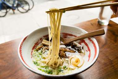 chopsticks plucking noodles out of a bowl of ramen