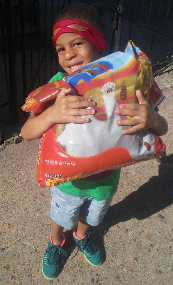 Little boy holding large bag of cat food