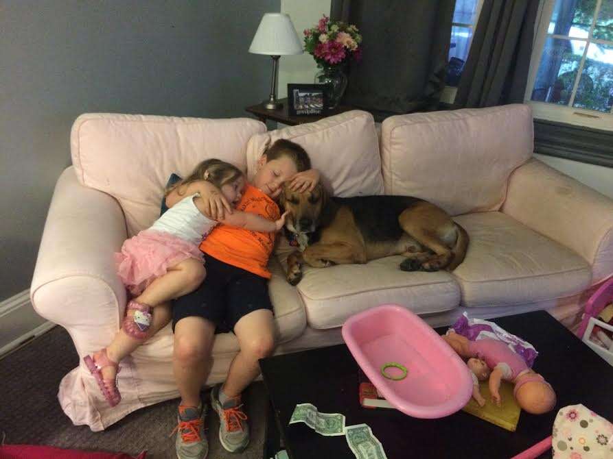 Kids cuddling with rescued hound