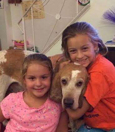 Girls cuddling rescued hound
