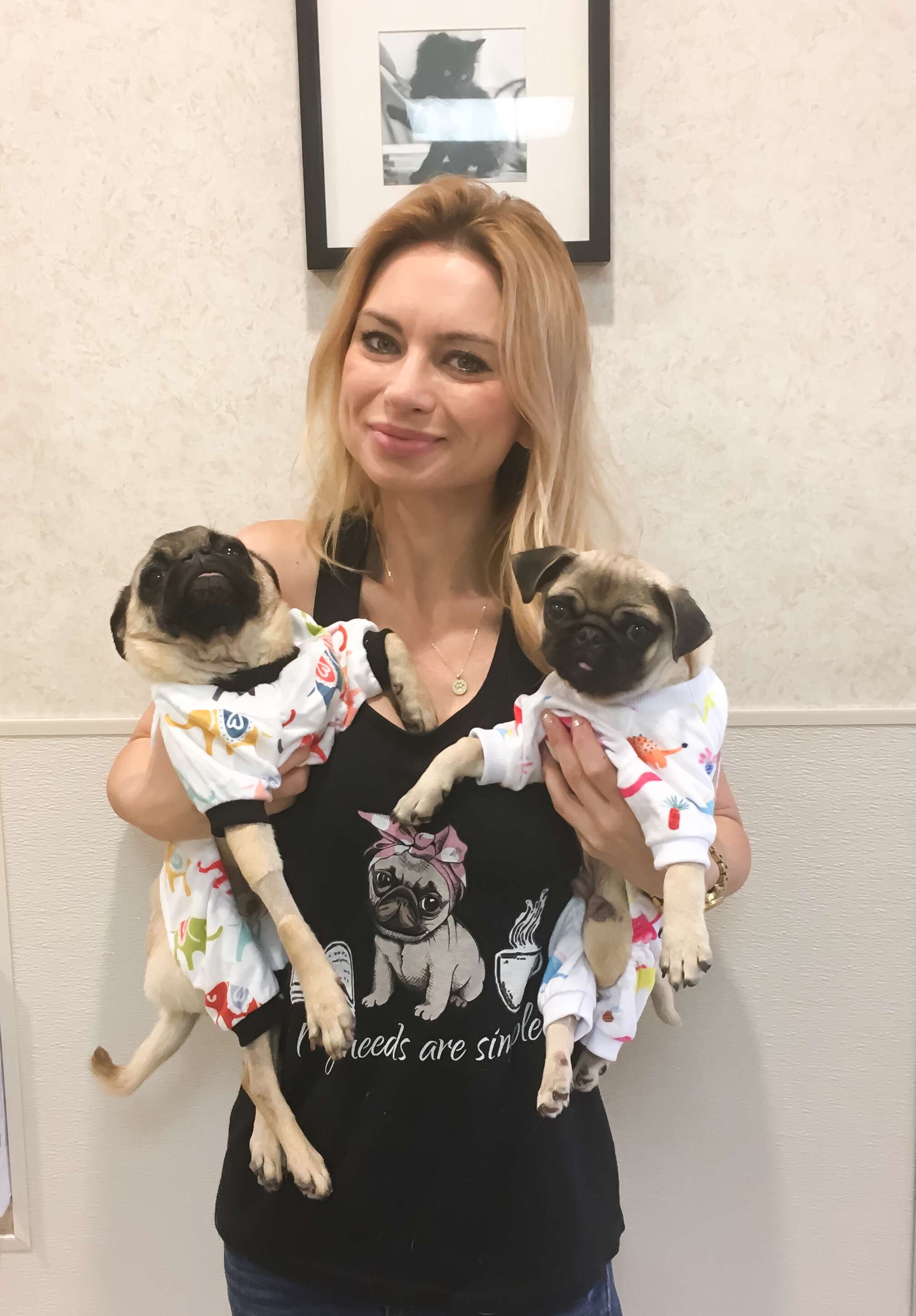 Woman holding two pugs in pajamas