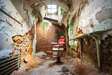 an old dilapidated room in a penitentiary with a chair
