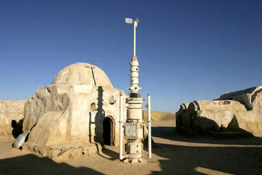 a dusty, futuristic structure and antenna in the desert