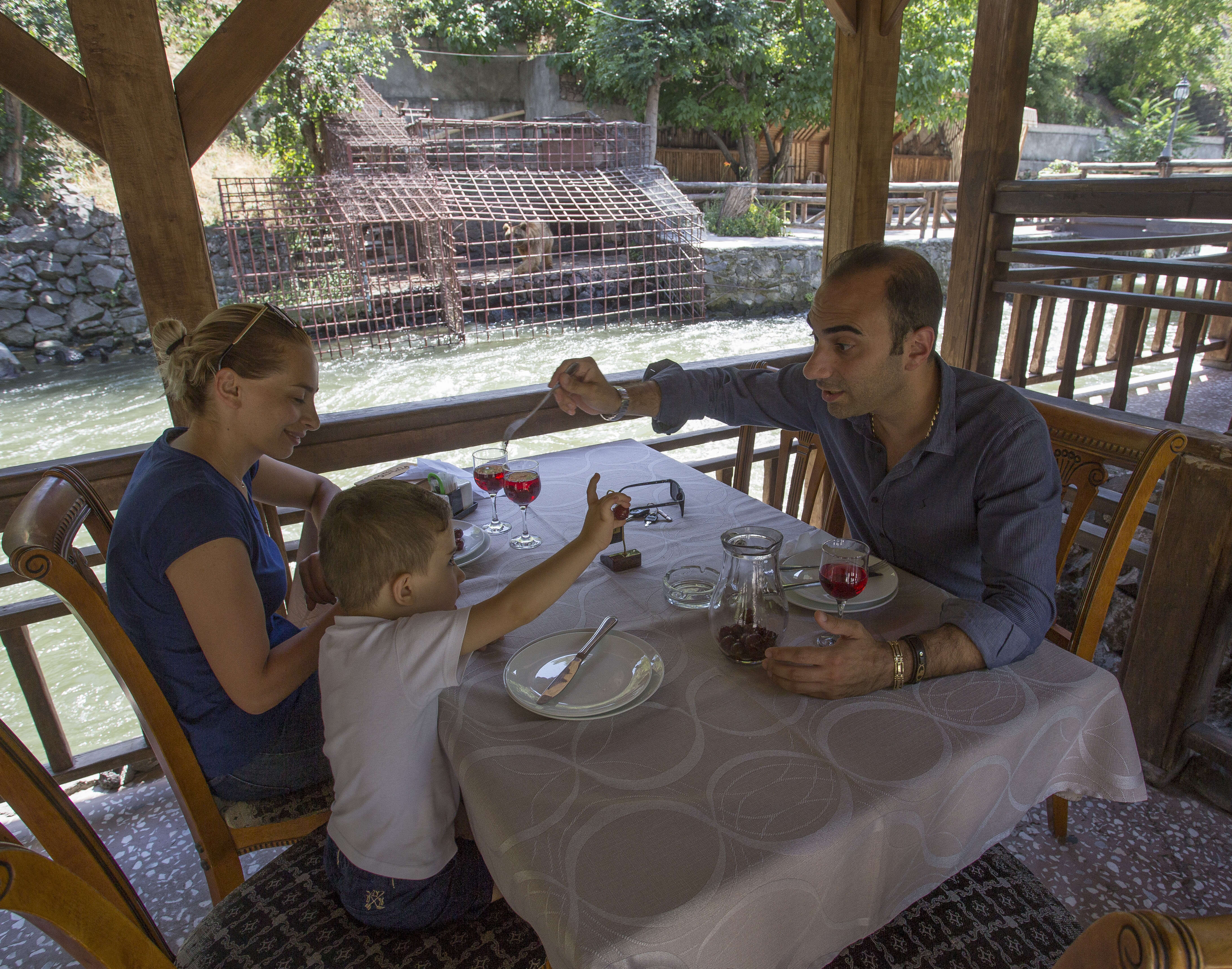 People dining at restaurant across from caged bears