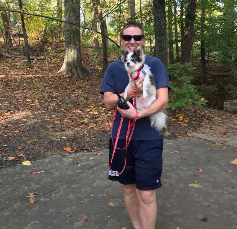 Firefighter holding small shelter dog in his arms
