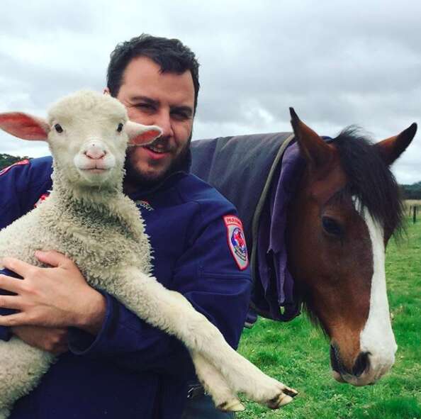 Man holding rescued lamb in his arms