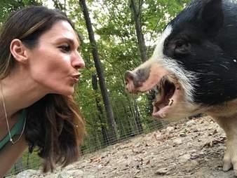 Woman ready to kiss a pig on the snout