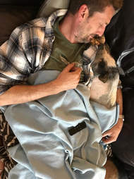Man cuddling pig in a blanket