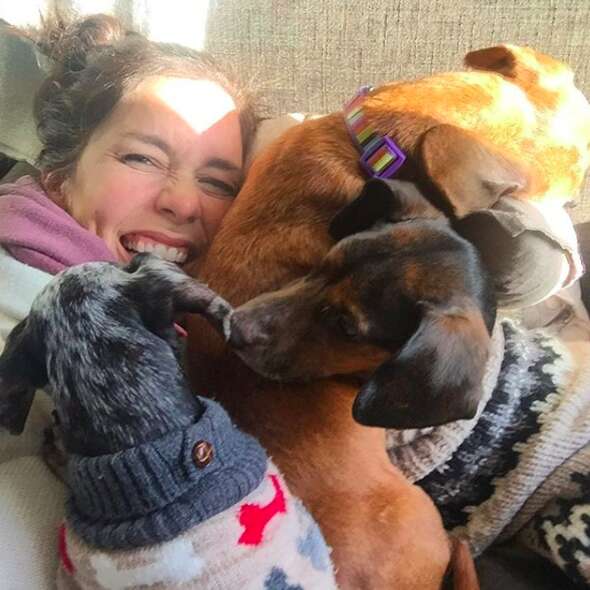 Woman cuddling with three dogs