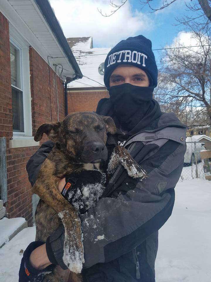 Man holding cold dog in the snow