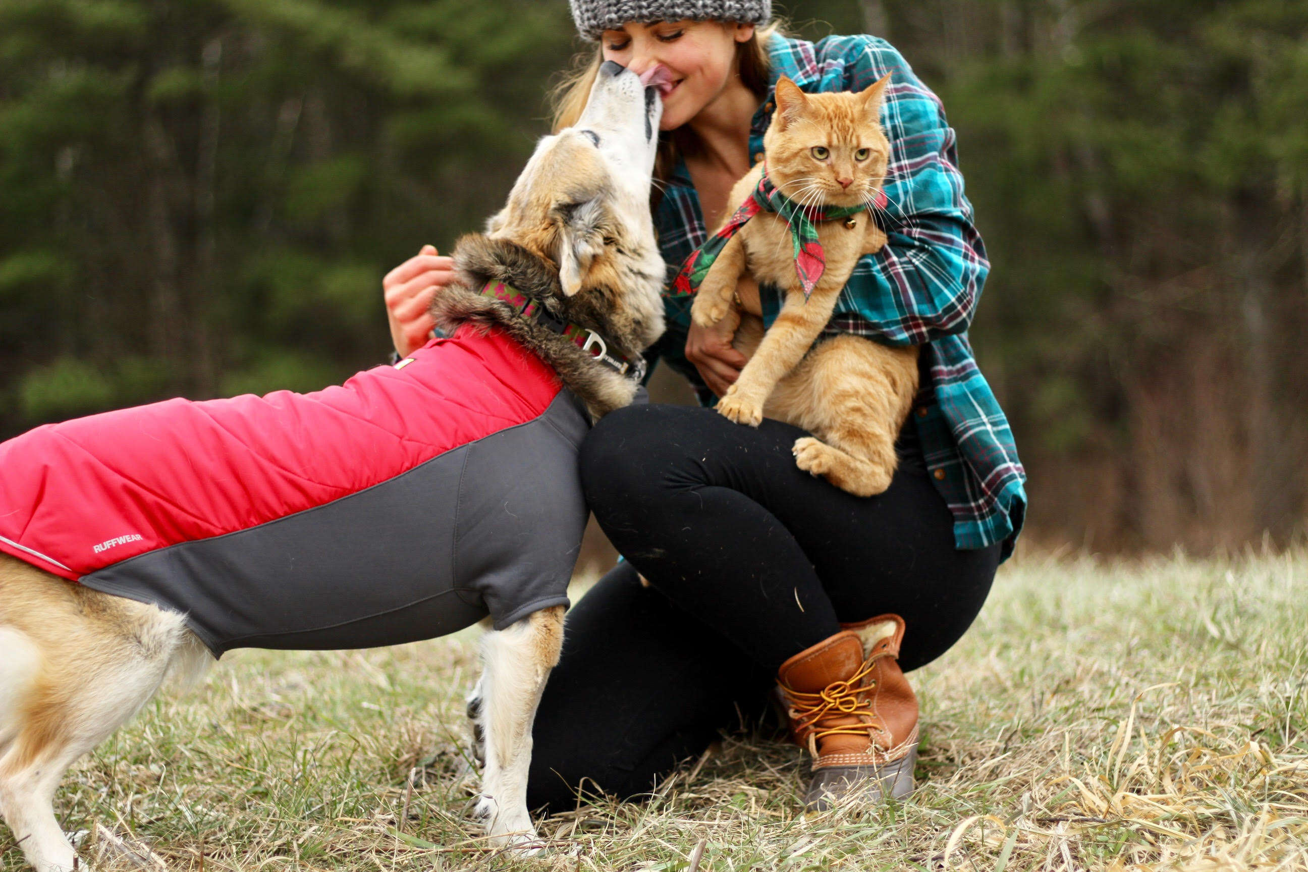 Woman hugging dog and cat outside