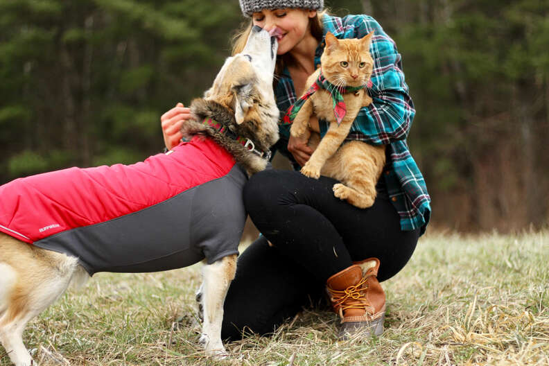 Woman hugging dog and cat outside